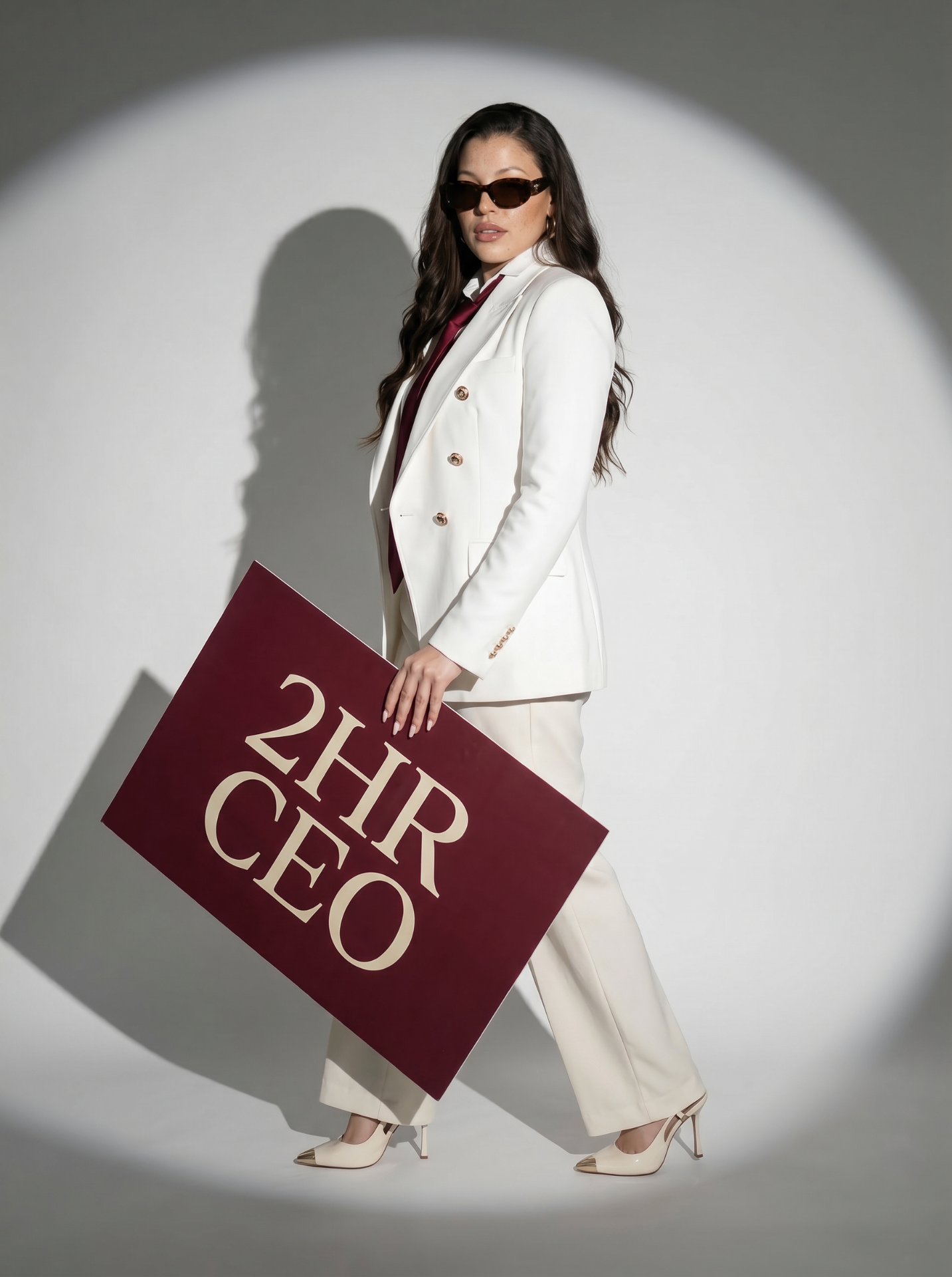 Paula in a white suit holding a 2HR CEO sign